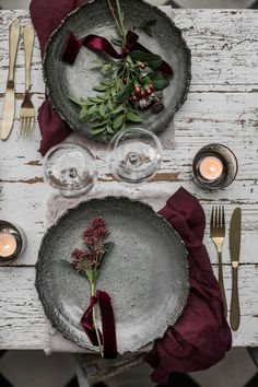 the table is set with silverware and red napkins, candles, and greenery