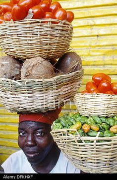 a man with baskets on his head and vegetables in front of him at an outdoor market