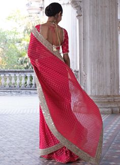 This look features a raspberry pink banarasi saree set. The flowy georgette has woven gold motifs with handcrafted sequin, mirror and pearl border. A matching embellished scoop neck blouse completes the look. Includes a satin underskirt Composition: Blouse - Viscose georgette, Saree - Viscose georgette , Underskirt - Satin Care: Dry Clean Only and Vacuum Storage This product can be customised for colour, sleeves, length of blouse and neck design Delivery : 2 weeks as the product is hand crafted. For more information and sizes please contact fabiliciousfashion@gmail.com or visit our Copenhagen studio. About the Designer : Renee Label was created in 2013,by the talented sister duo Pooja and Karuna, is a culmination of their love for fashion and art. The mesmerizing wedding wear collection th Party Banarasi Silk Pre-draped Saree With Dupatta, Elegant Saree With Gota Work In Chinon, Elegant Pink Choli With Zari Weaving, Elegant Georgette Saree With Gota Work, Party Silk Choli With Zari Weaving, Party Banarasi Silk Blouse Piece In Pink, Pink Banarasi Silk Blouse Piece For Party, Bollywood Georgette Sets With Zari Weaving, Designer Wear Choli With Zari Weaving In Georgette