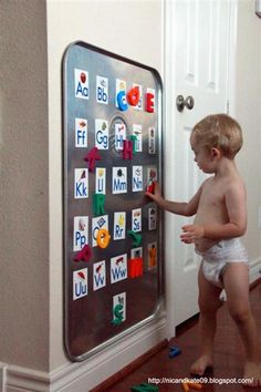 a little boy that is standing in front of a magnet board