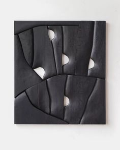 an art piece with black and white shapes on the wall in front of a white wall