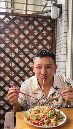 a man sitting at a table with a plate of food in front of his mouth