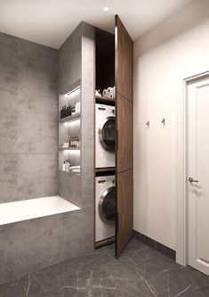 a washer and dryer in a bathroom next to a bathtub with shelves on the wall