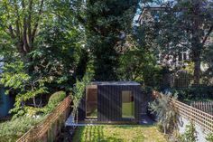 a small house in the middle of a yard with trees and bushes on both sides