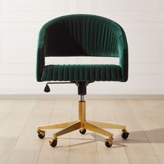 a green velvet office chair sitting on top of a hard wood floor next to a white wall