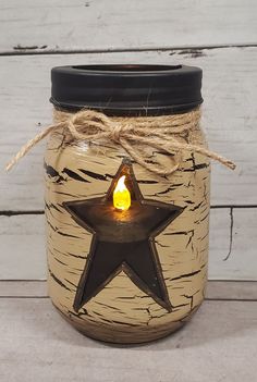 a mason jar with a lit candle in the shape of a star is on a wooden table