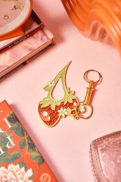 a close up of a key chain on a table with books and a clock in the background