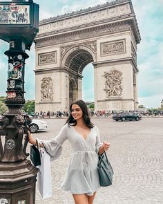 a woman standing in front of the arc de trioe