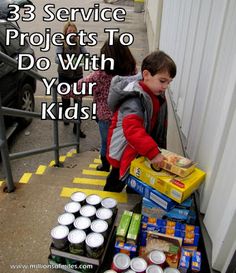 a young boy standing in front of a table filled with boxes and cups next to a building