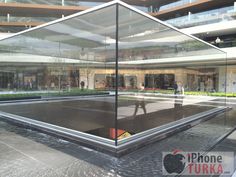 an empty tennis court in the middle of a building with lots of people walking around it