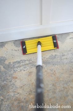 a yellow and black pole laying on the ground next to a door with a hole in it