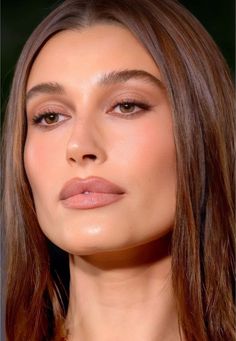 a woman with long hair wearing an orange necklace and brown eyeshadow is looking off to the side