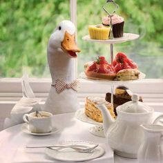 there is a duck that is sitting on the table with some cakes and cupcakes