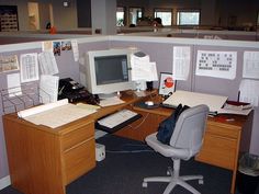 an office cubicle with a computer, keyboard and monitor