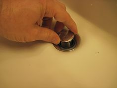 a hand is pressing the button on a sink faucet