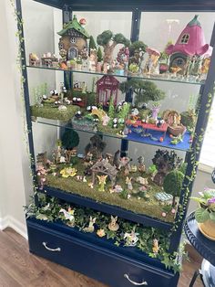 a display case filled with lots of little fairy figurines on top of blue drawers