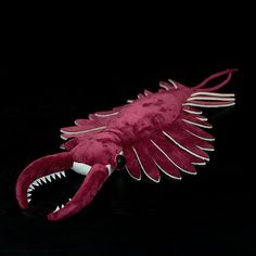 a stuffed animal that looks like a fish with its mouth open and teeth out, on a black background