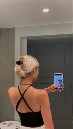 a woman taking a selfie in front of a mirror with her cell phone up to her ear