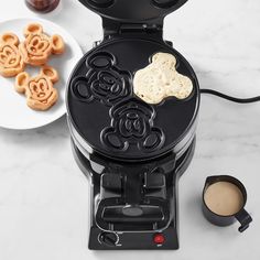 a mickey mouse waffle maker next to some cookies