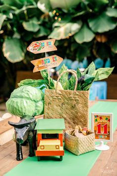 a table topped with a basket filled with lots of green vegetables next to a sign