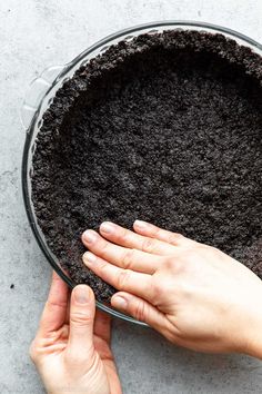 someone is holding their hand over the top of a pie pan with dirt in it