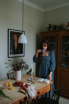 a woman standing in front of a table with an open book and candle on it