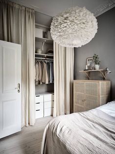 a bedroom with a bed, dresser and hanging light fixture in the middle of it