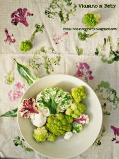 broccoli florets and cauliflower in a bowl on a floral tablecloth