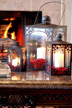 three lit candles sitting on top of a table next to a fire place and books