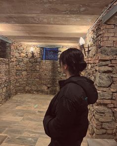 a woman is standing in an empty room with bricks on the walls and stone floors