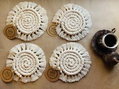 four woven coasters with wooden tags on them next to a teapot and vase