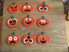 six pumpkins with different faces are arranged on a wooden table next to a bottle opener