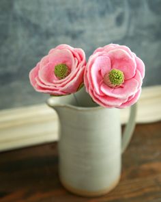 two pink flowers are in a white vase