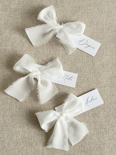 three white bows with name tags attached to them