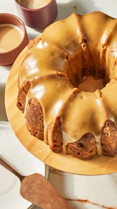 a bundt cake sitting on top of a wooden plate next to a cup of coffee