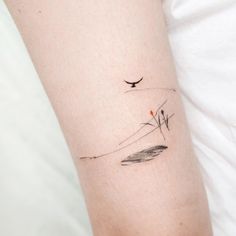 a woman's arm with a small bird tattoo on the left side of her arm