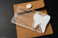 a badge with a tooth on it sitting on top of a leather card holder in front of a black surface