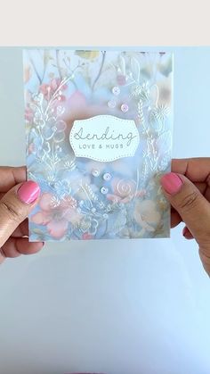 two hands holding up a card that says sending love and hugs with flowers on it