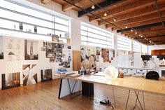 an office with wooden floors and lots of pictures on the wall, including desks