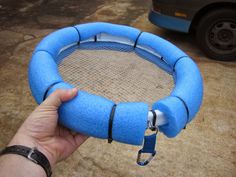 a person holding up a blue object in front of a car