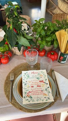 a place setting with tomatoes, basil and spaghetti on the table for an italian dinner