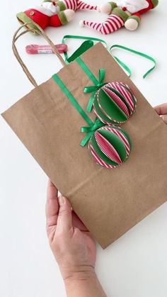 a person holding a brown paper bag with christmas decorations on it and some candy canes