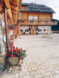 a wooden house with red flowers in front of it and a stone walkway leading up to the building