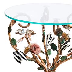 a glass table with flowers and leaves on it's base, against a white background