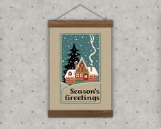 a cross stitch christmas card hanging on a wall