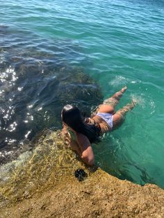 a woman is swimming in the water near rocks