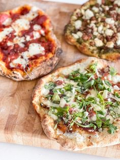 three different types of pizza on a cutting board