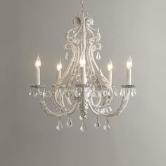 a white chandelier with crystal drops hanging from it's sides and candles in the middle