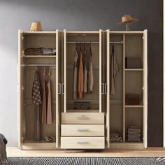 an open closet with clothes hanging on the doors and drawers in front of it, next to a bed