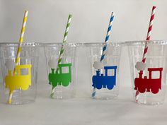 four plastic cups with different colored straws in them and one has a train on the side